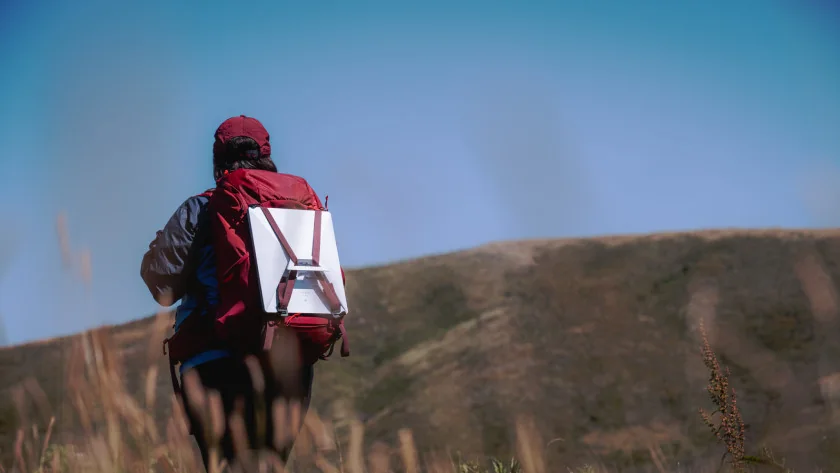 Mobile field worker carrying compact Starlink hardware in a remote landscape